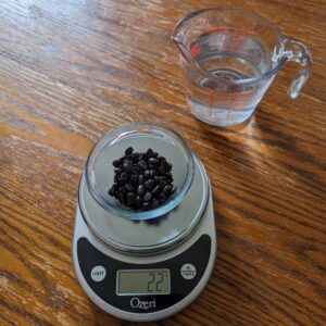 kitchen scale with a glass bowl of coffee beans and a measuring cup filled with 500 mL of water